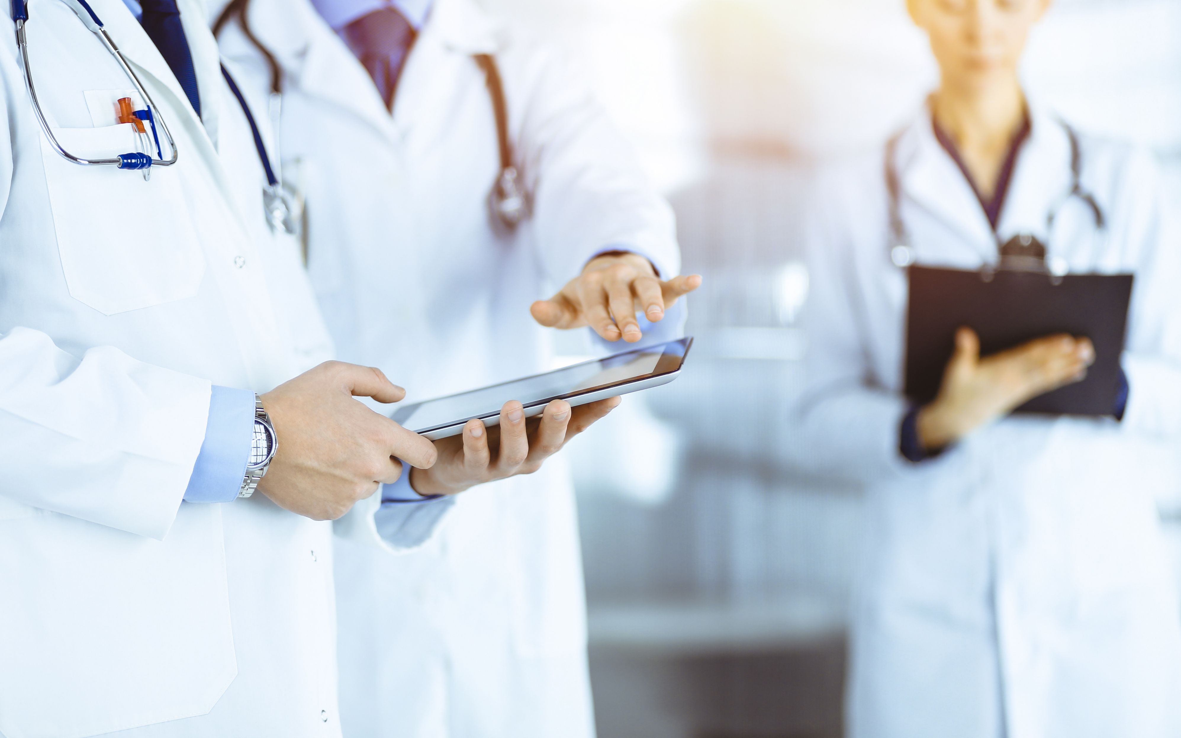 Two clinicians reviewing records on a tablet and clipboard