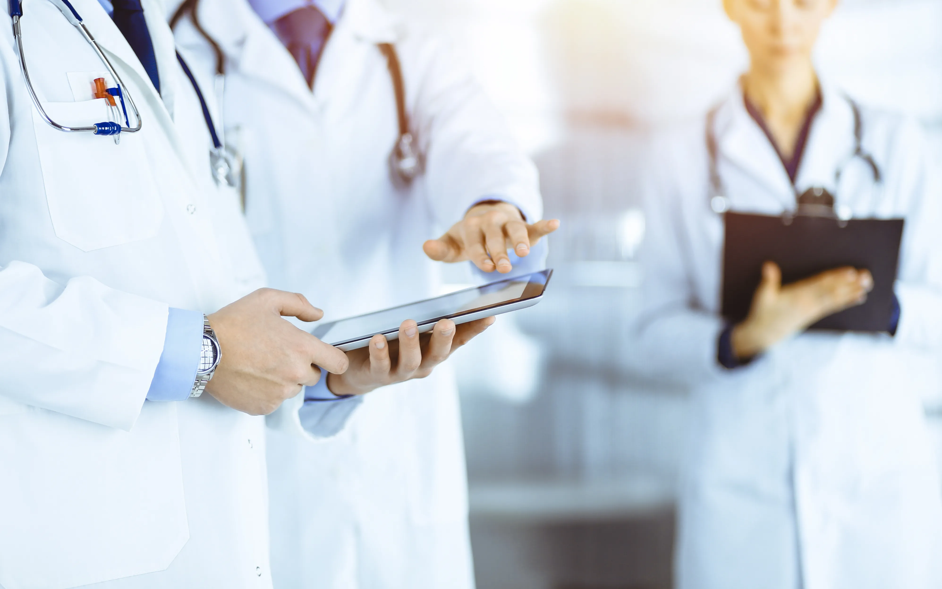 Two clinicians reviewing records on a tablet and clipboard