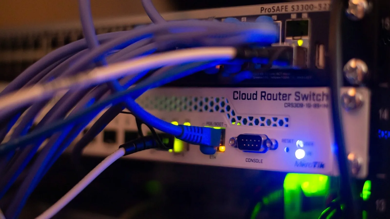 Network cables plugged into a router switch, lit by blue and green status lights
