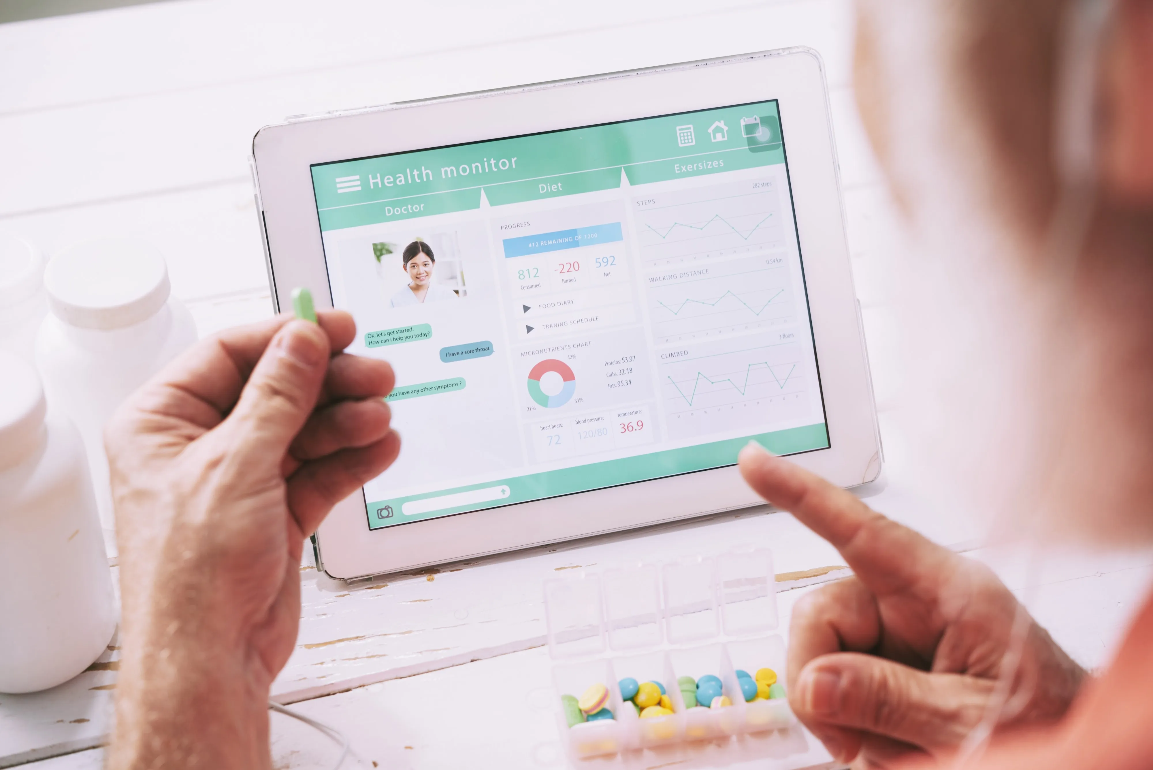A health monitoring app on a tablet beside a pill organizer