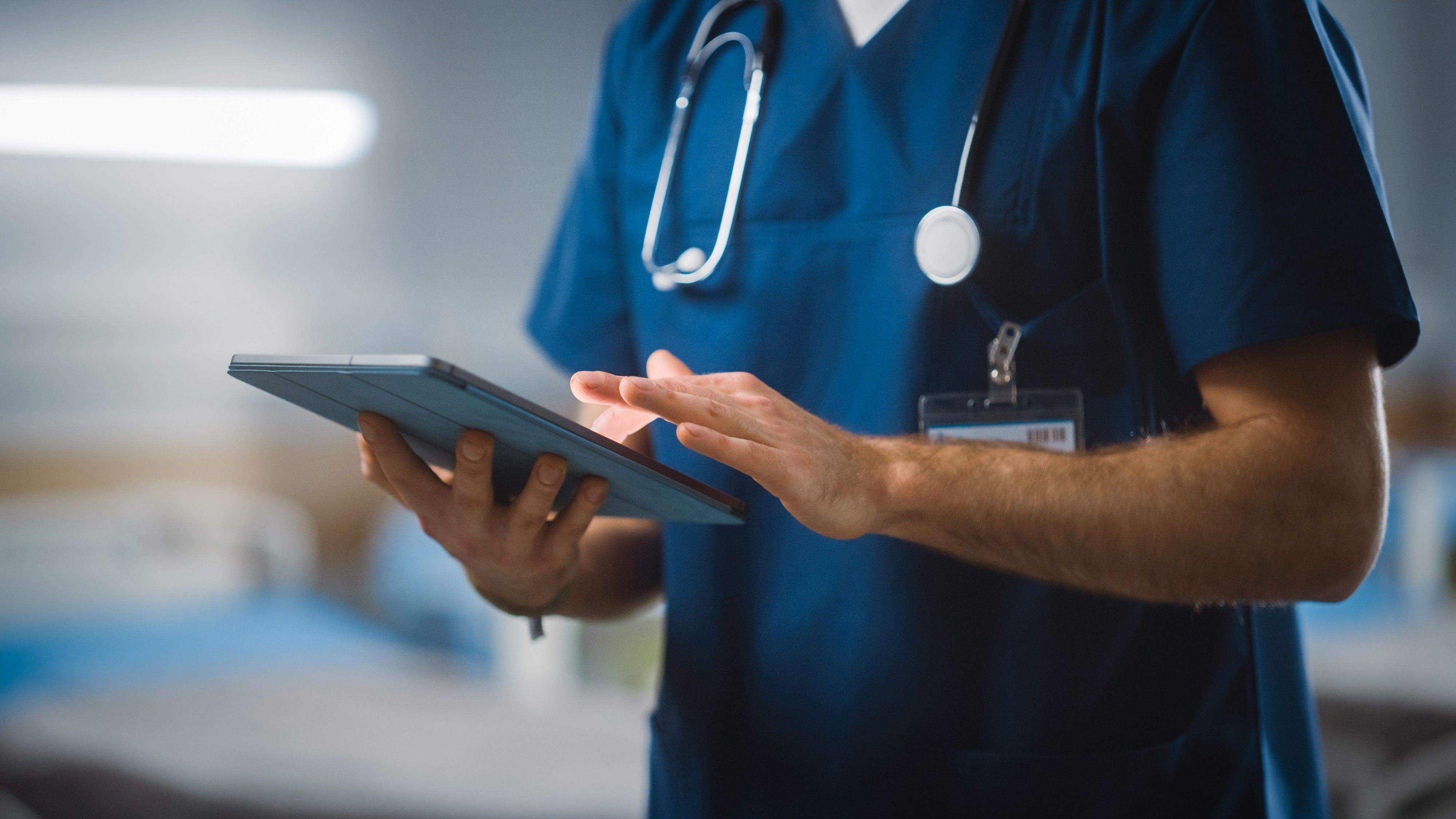 A clinician in scrubs reviewing information on a tablet
