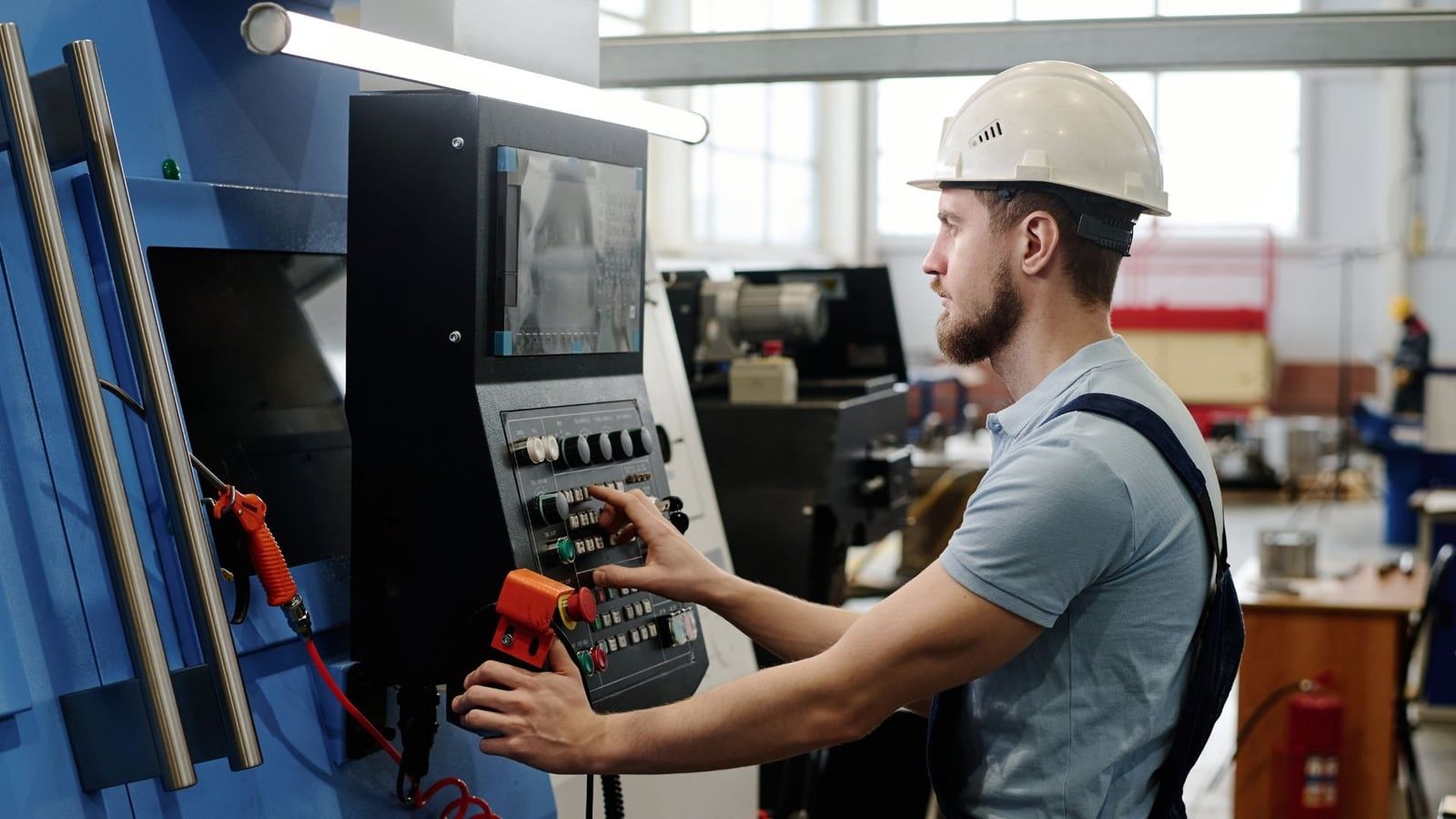 A machinist working at a CNC machine control panel