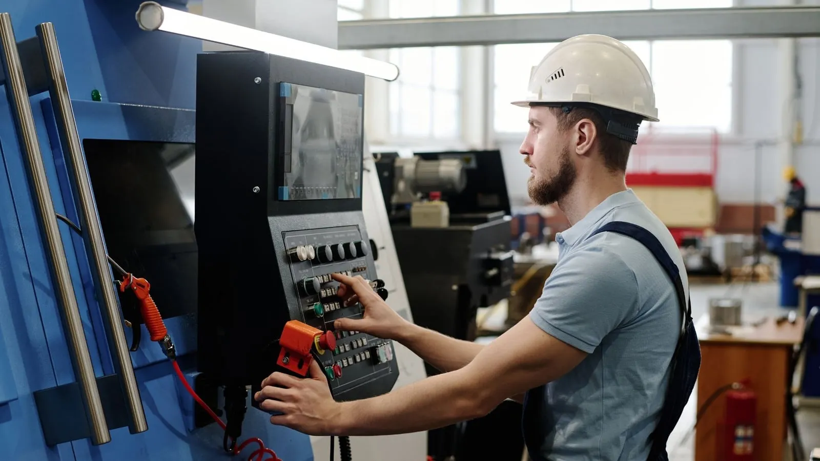 A machinist working at a CNC machine control panel
