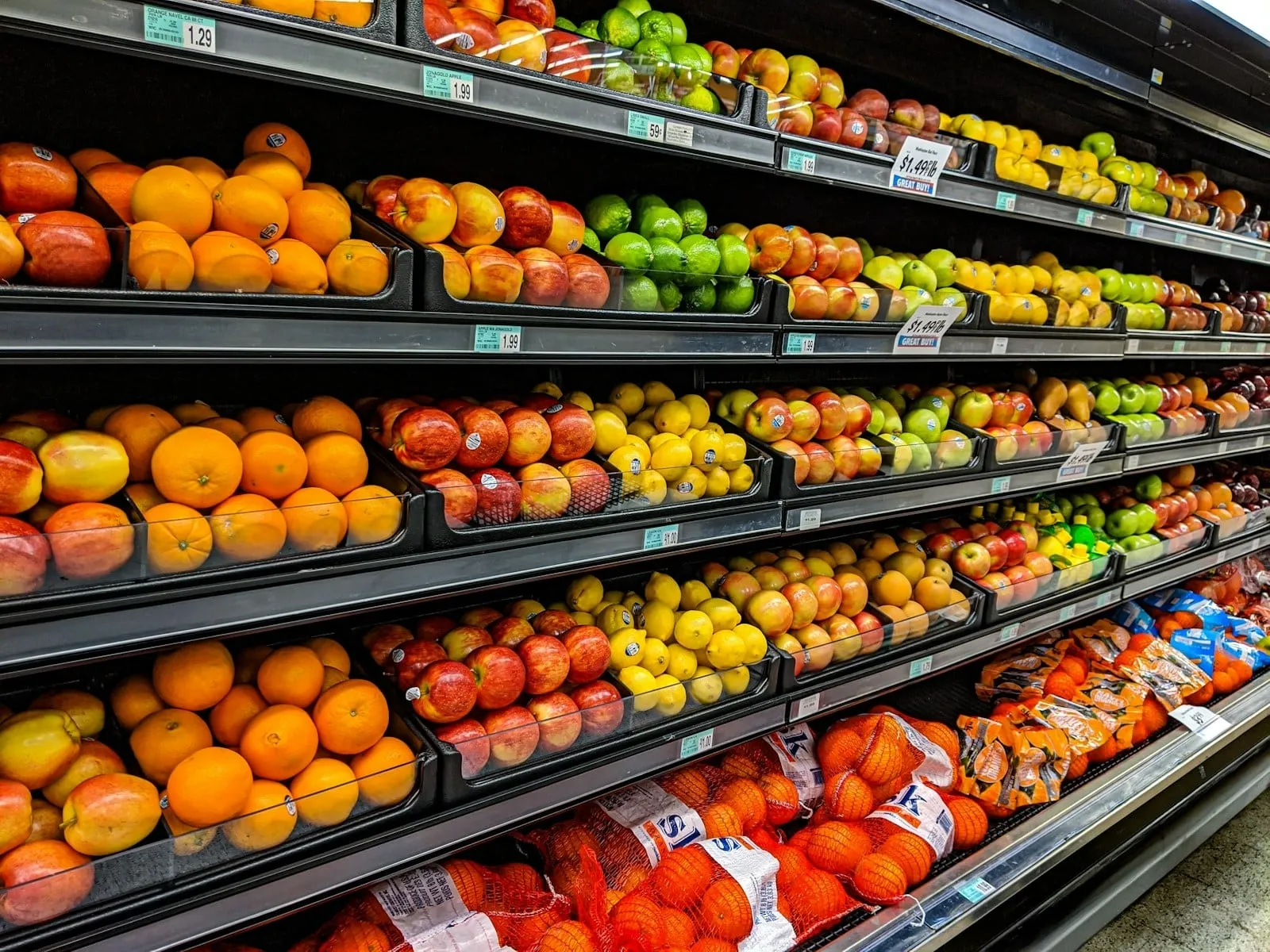 Grocery shelves stocked with oranges, apples and other fruit