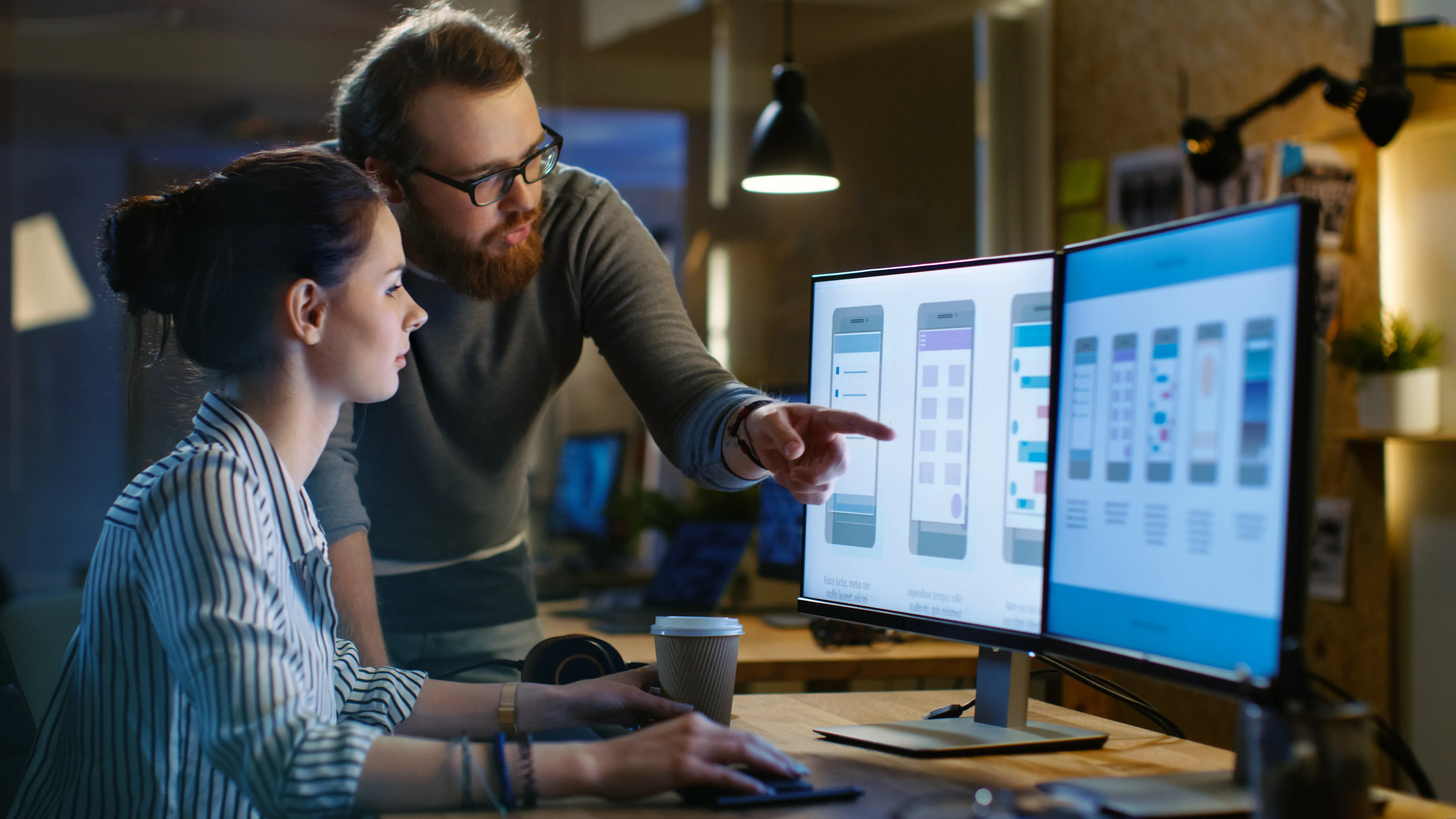 Two engineers reviewing dashboards on large monitors