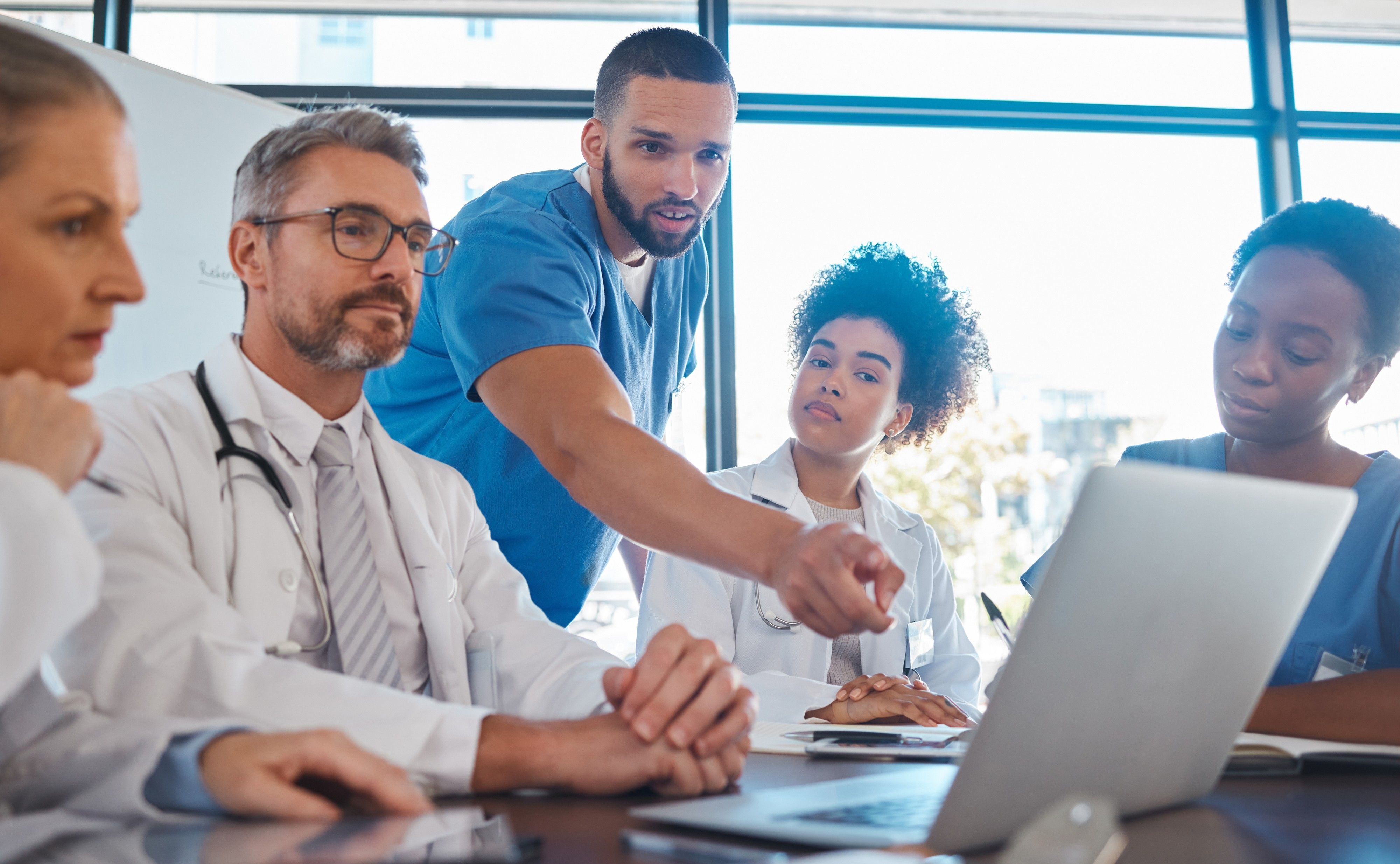 A clinical team meeting around a laptop