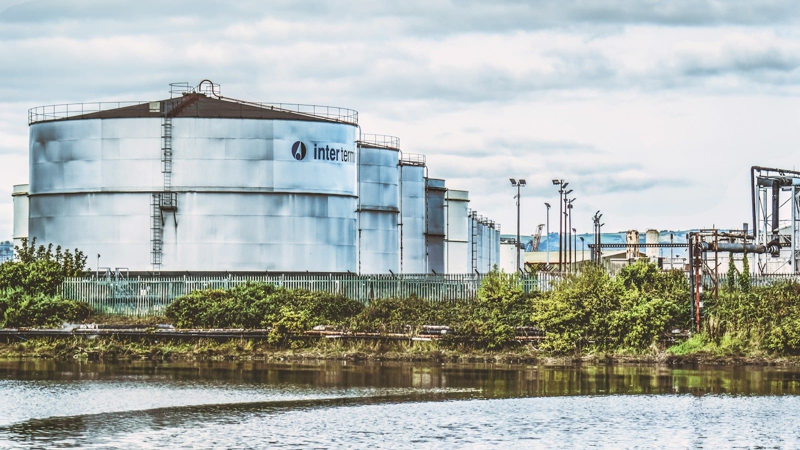 Industrial chemical storage tanks beside a river