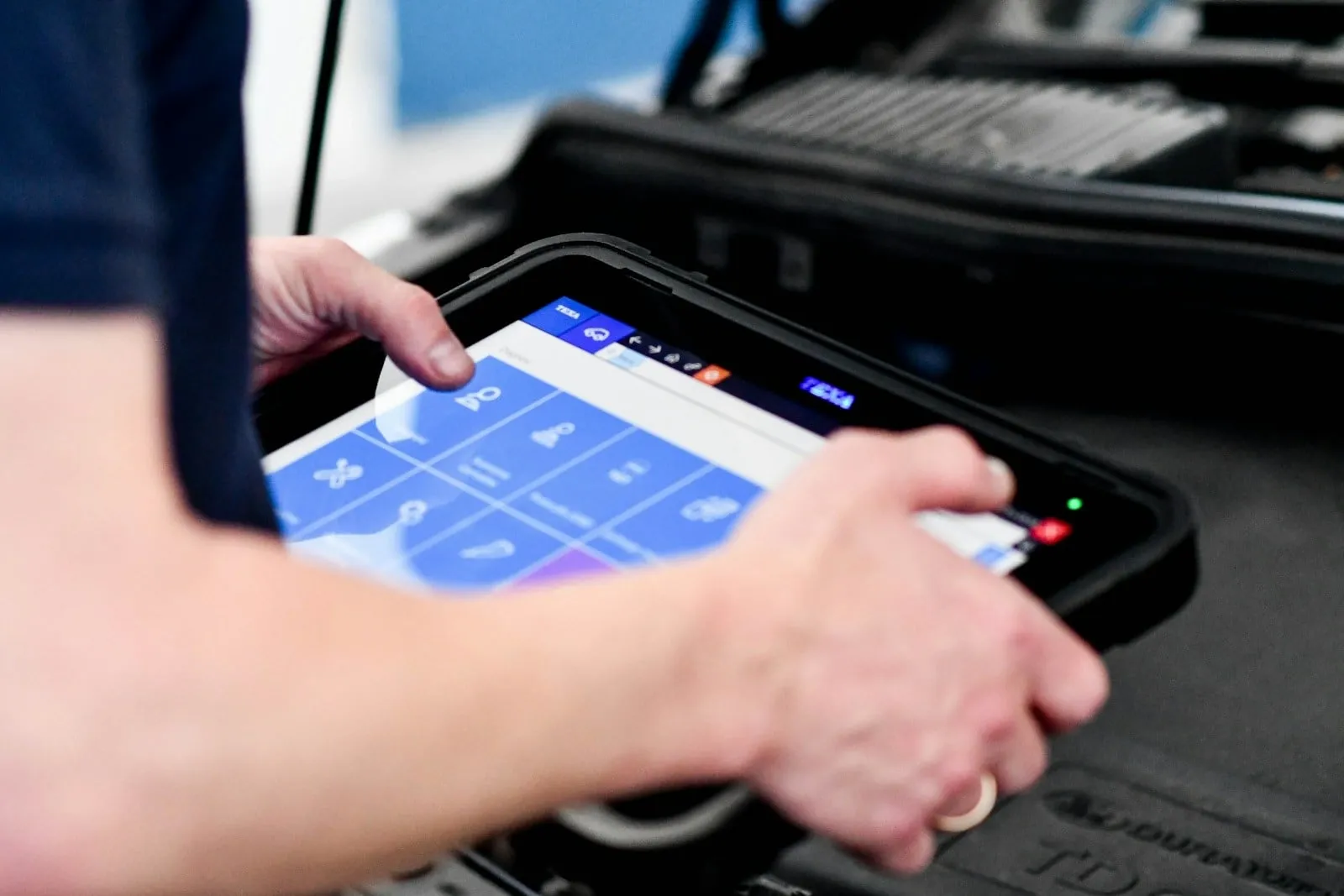 A field technician tapping a rugged tablet in a carrying case
