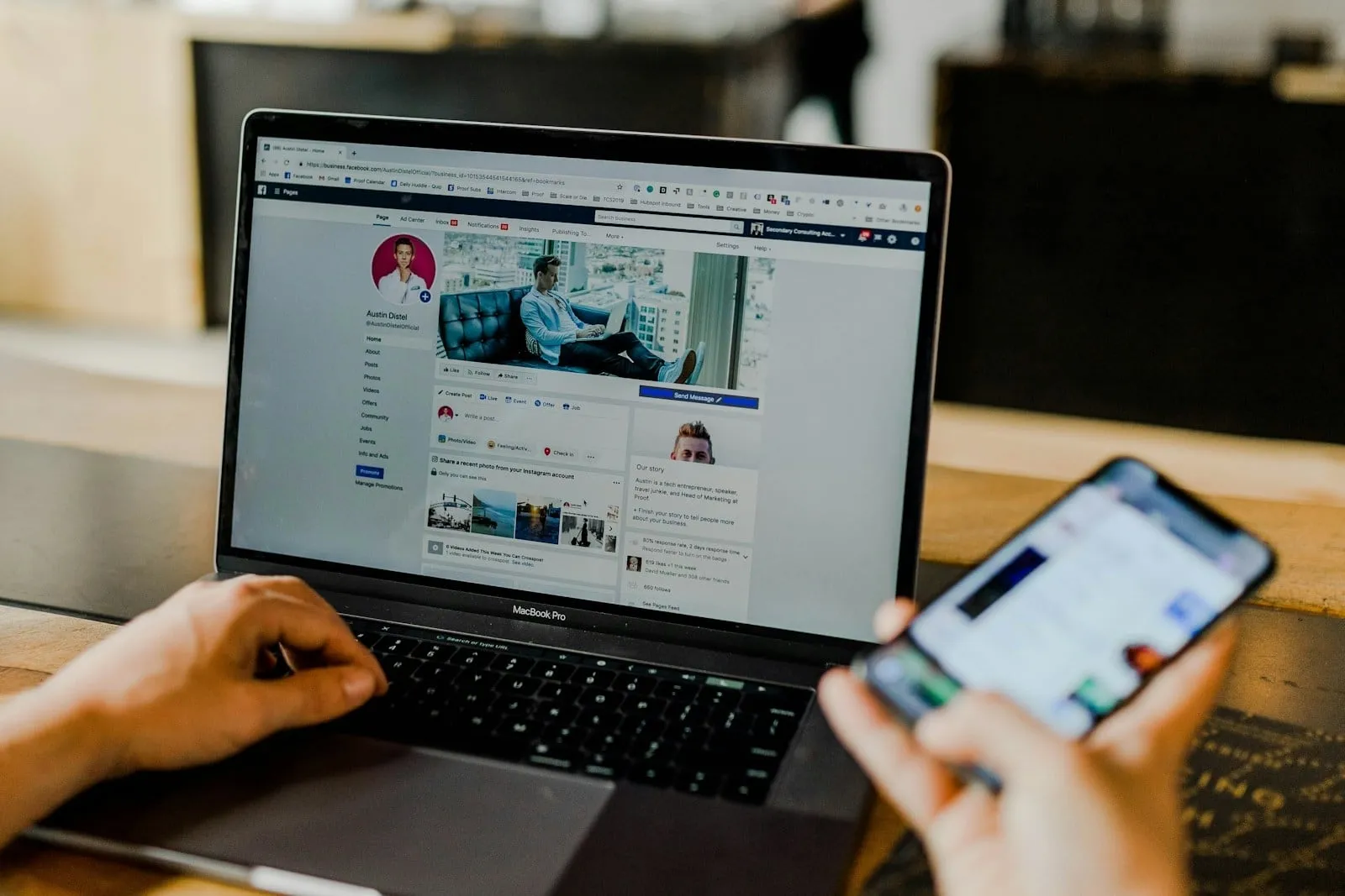 A person using a laptop with a social media profile open while holding a phone