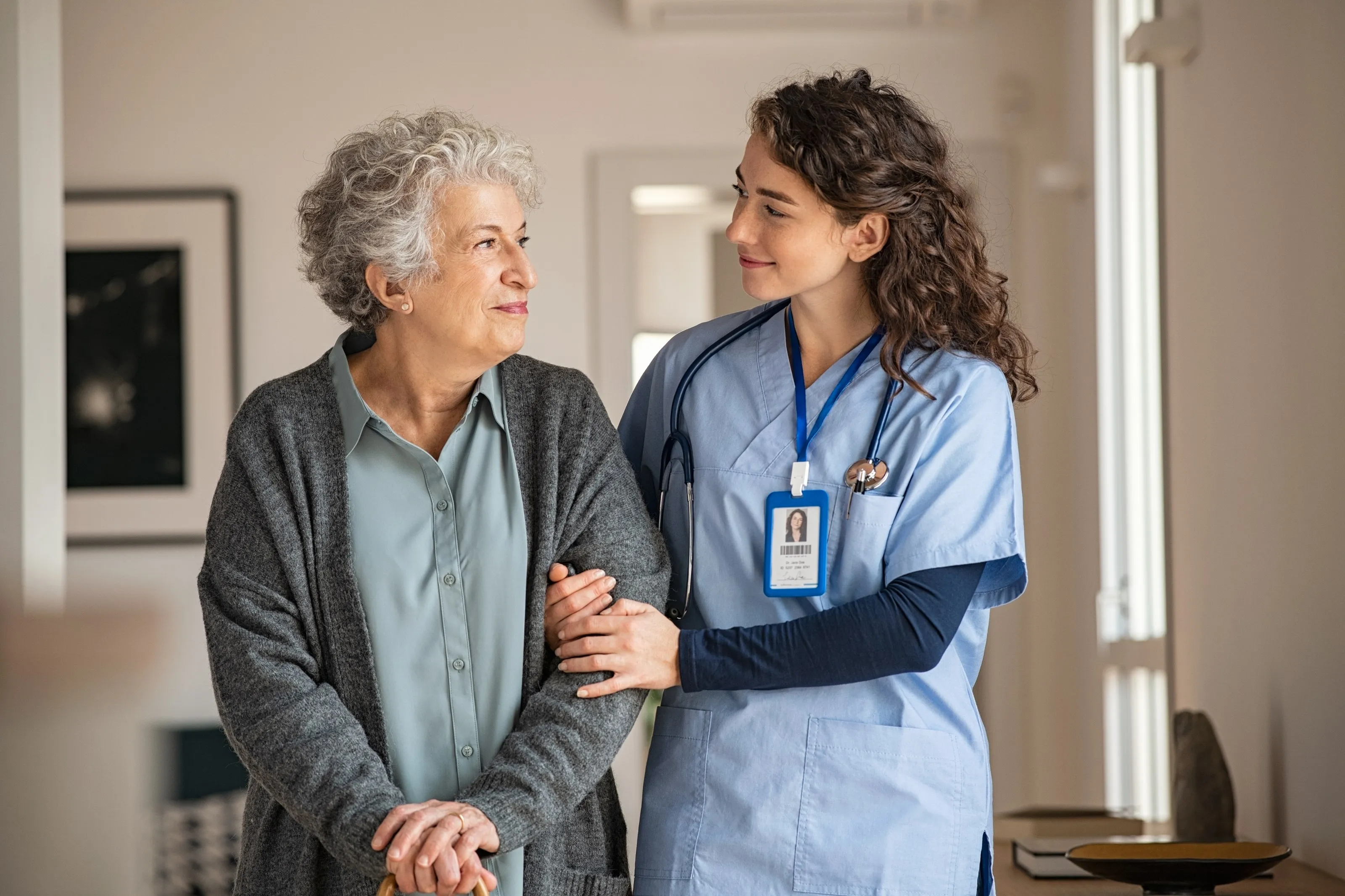 A caregiver walking arm in arm with an older woman