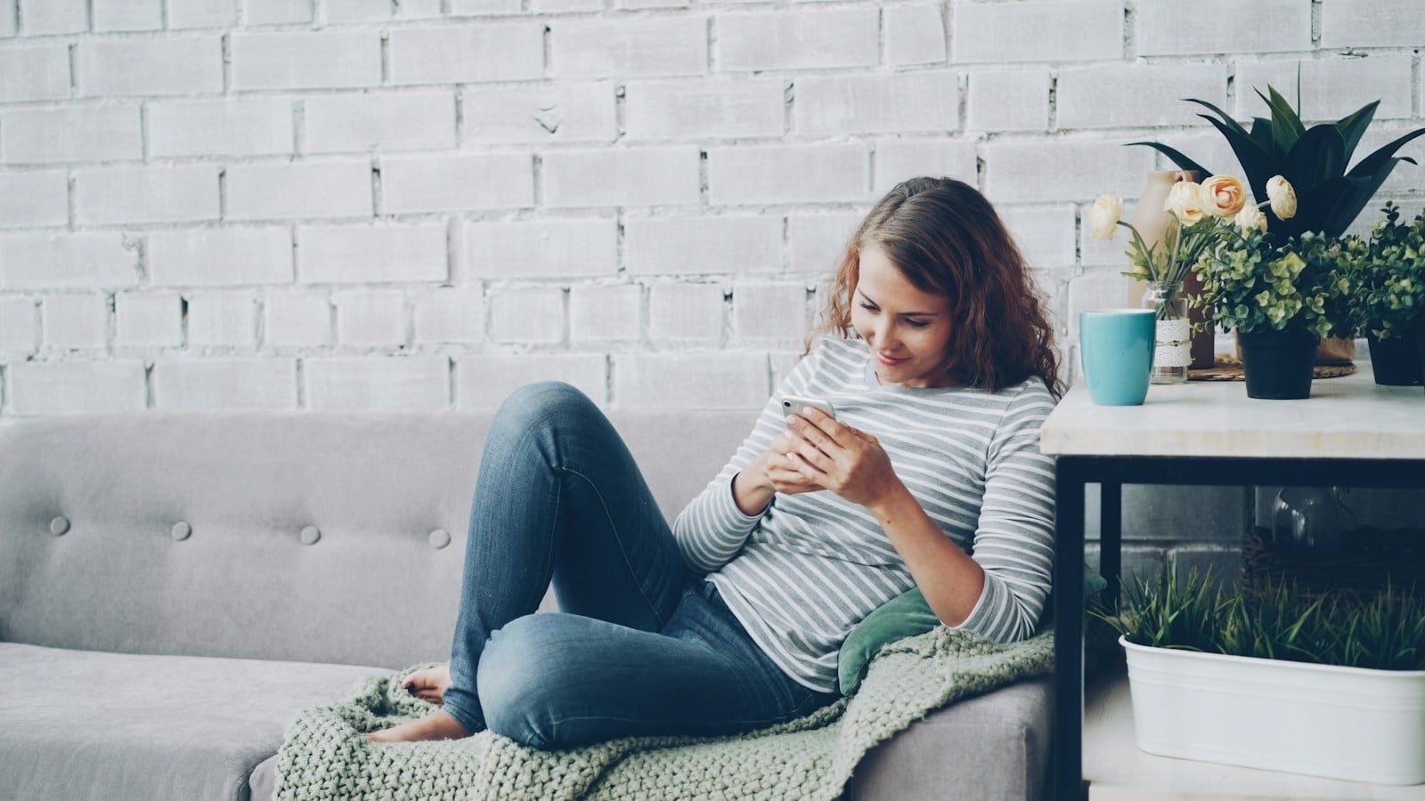 A woman relaxing on a sofa while checking her phone