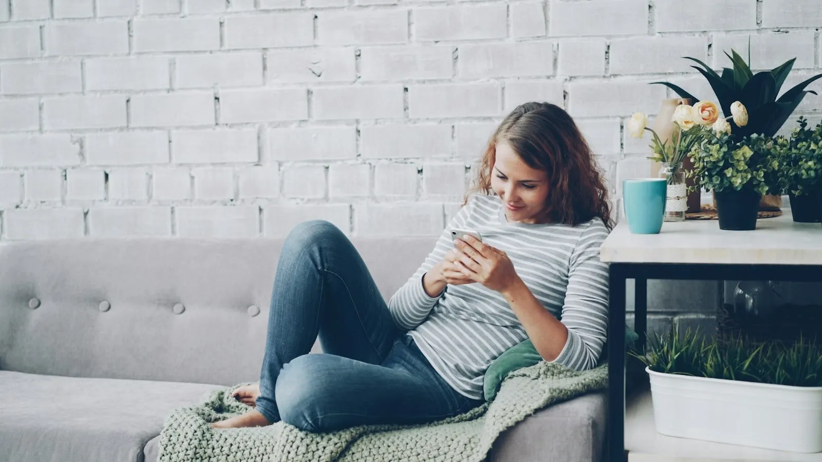 A woman relaxing on a sofa while checking her phone