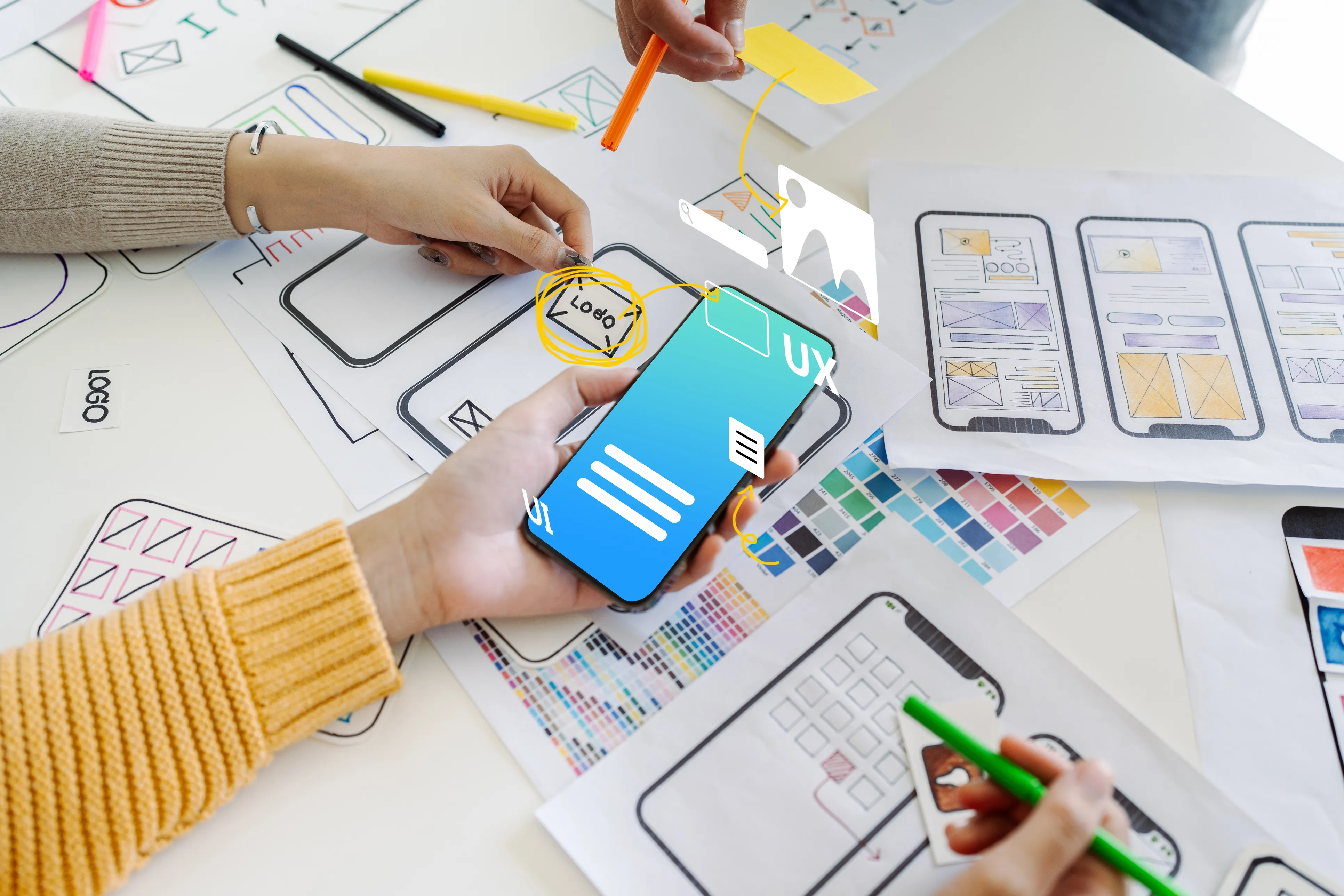 Mobile app screens and wireframes on a desk