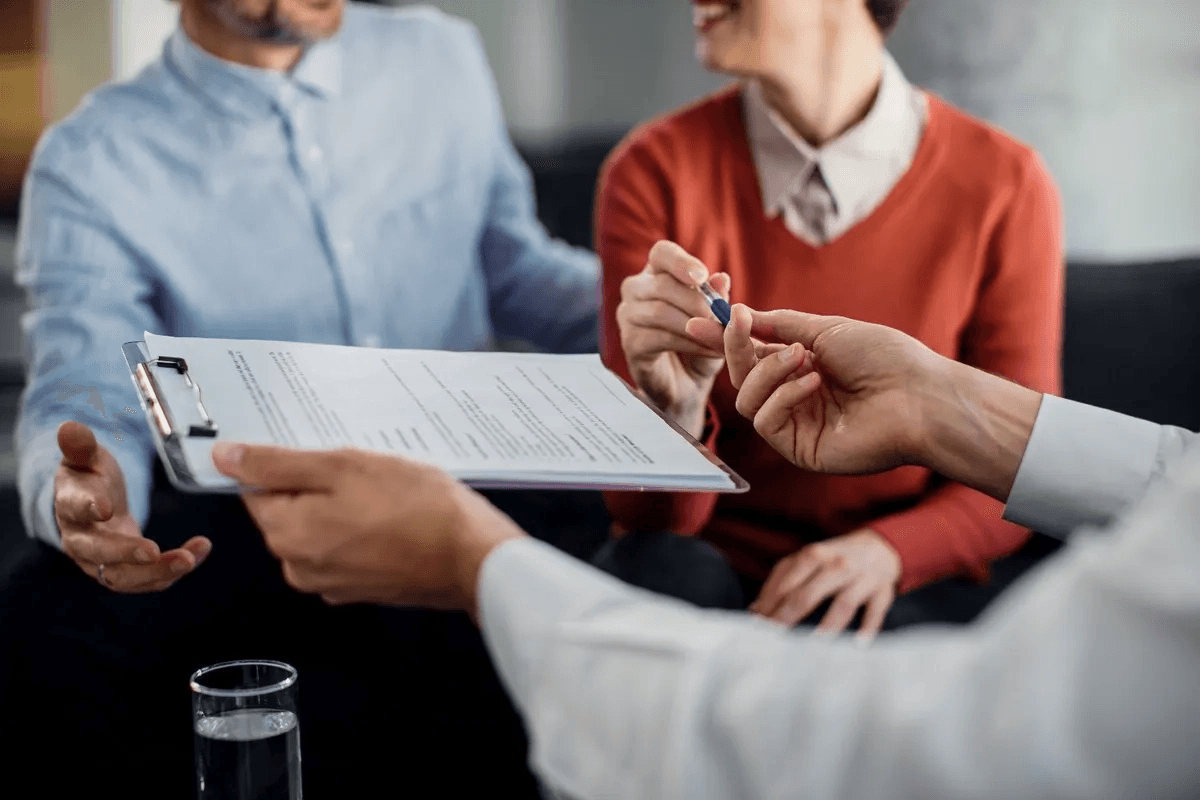 A clipboard form handed across a table during an intake meeting