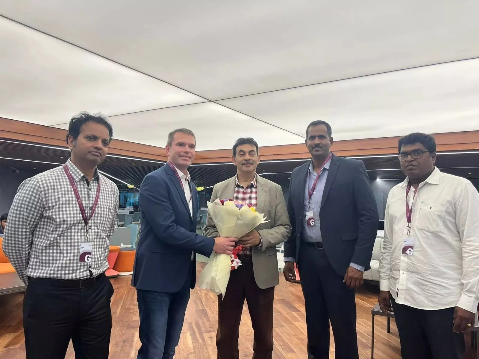 Five team leaders standing together in an office, one holding a welcome bouquet