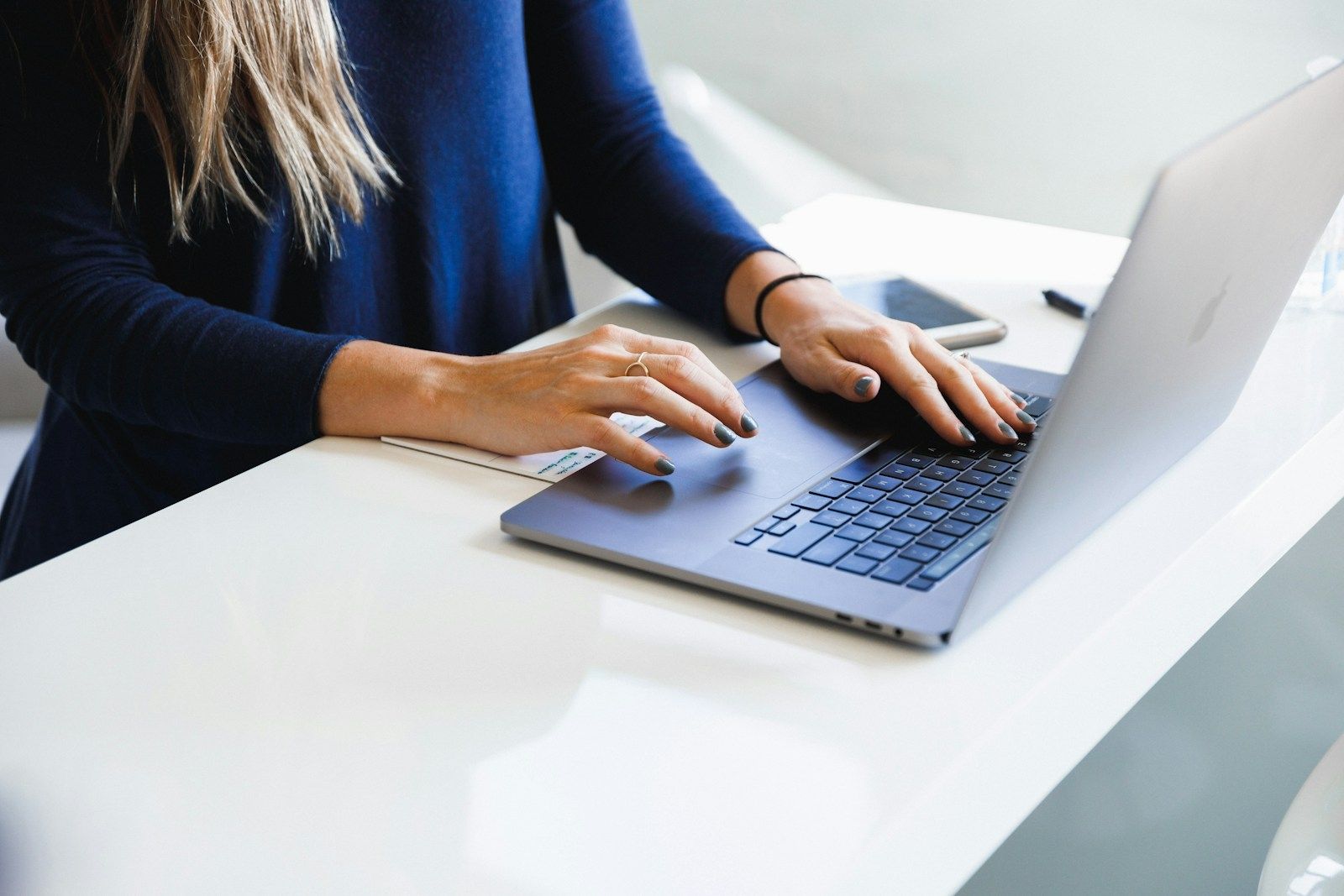 A person typing on a laptop at a white desk