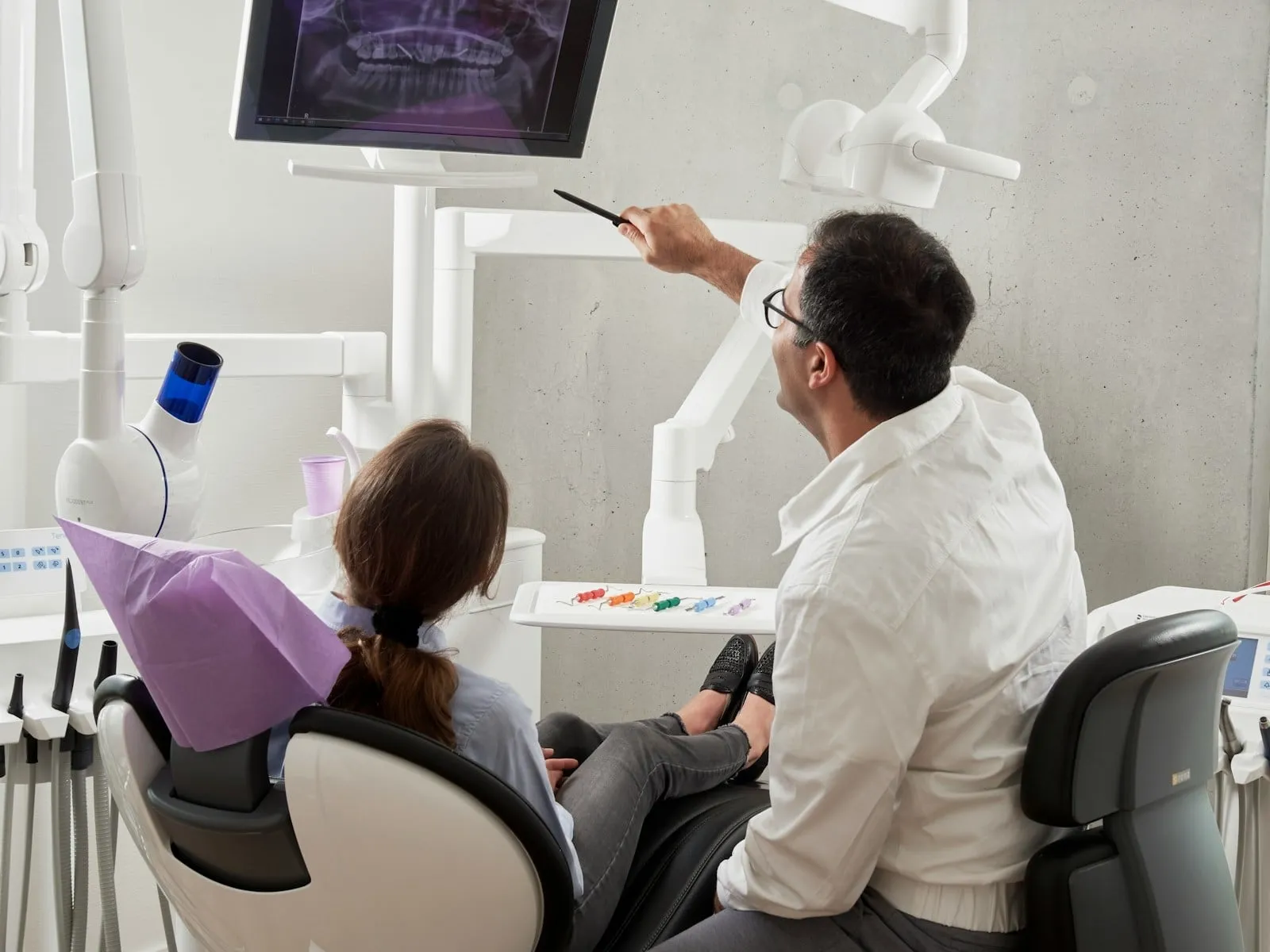 A dentist reviewing a scan on screen with a patient in the chair