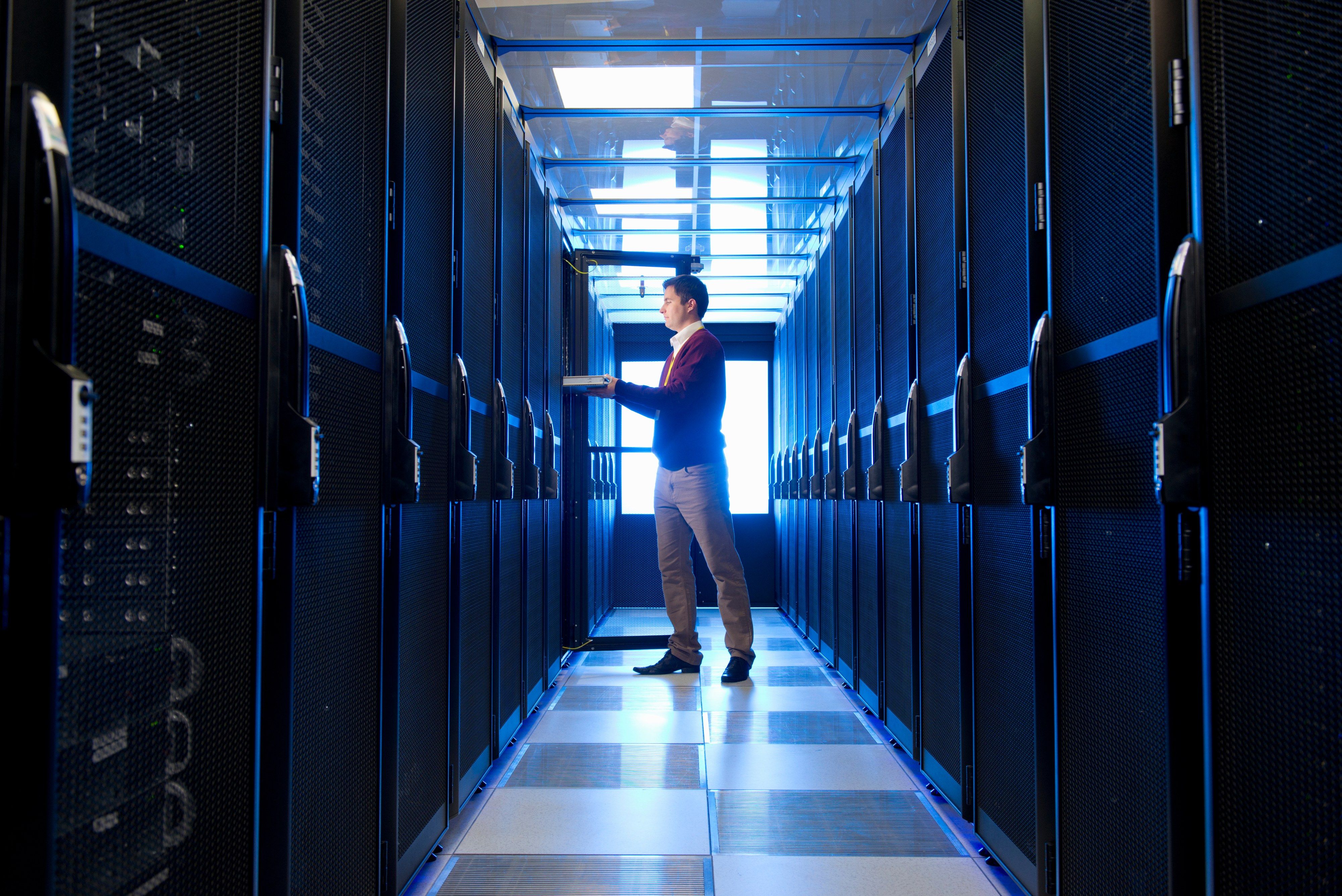 An engineer holding a server in a data center aisle
