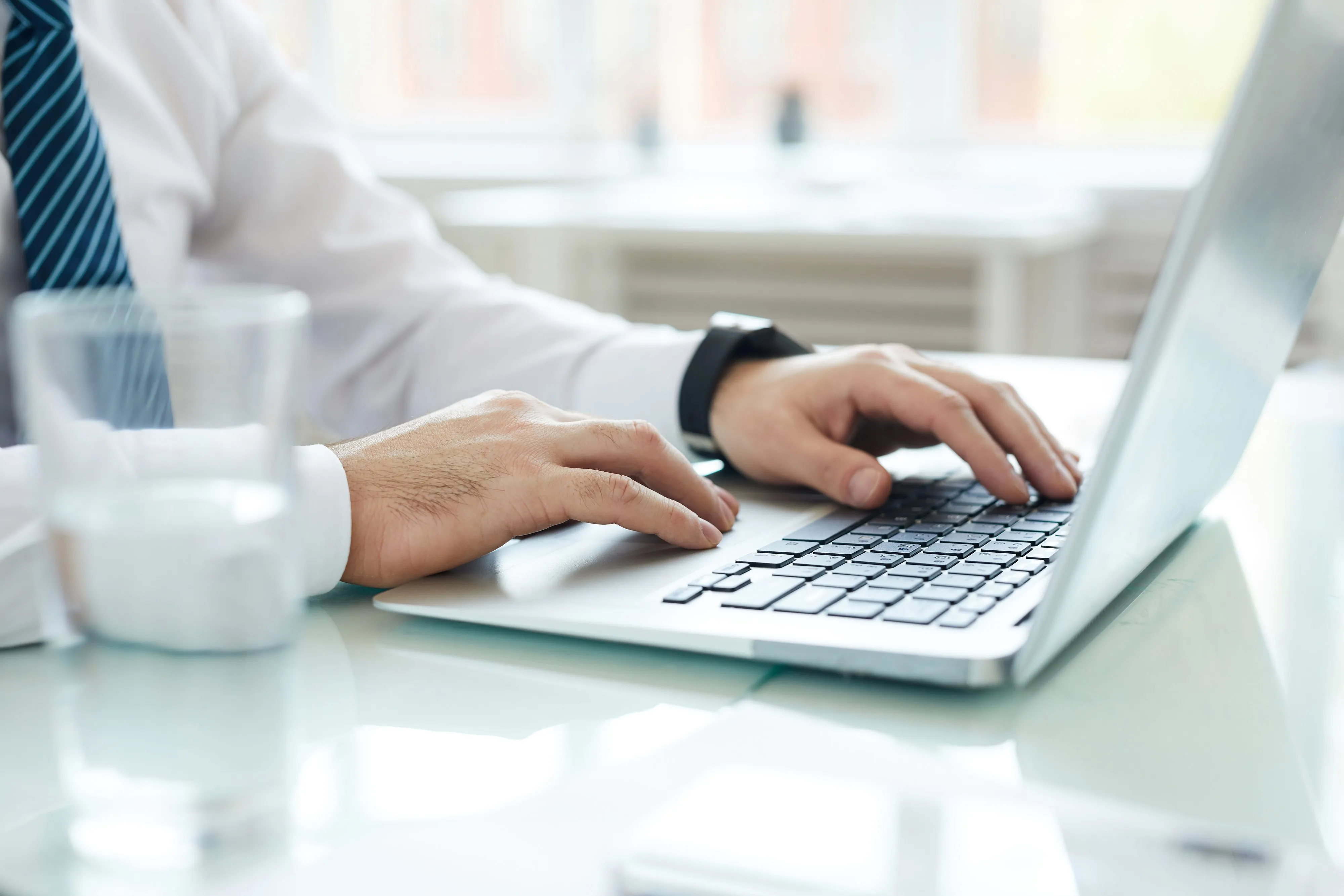 Hands typing on a laptop at a bright desk