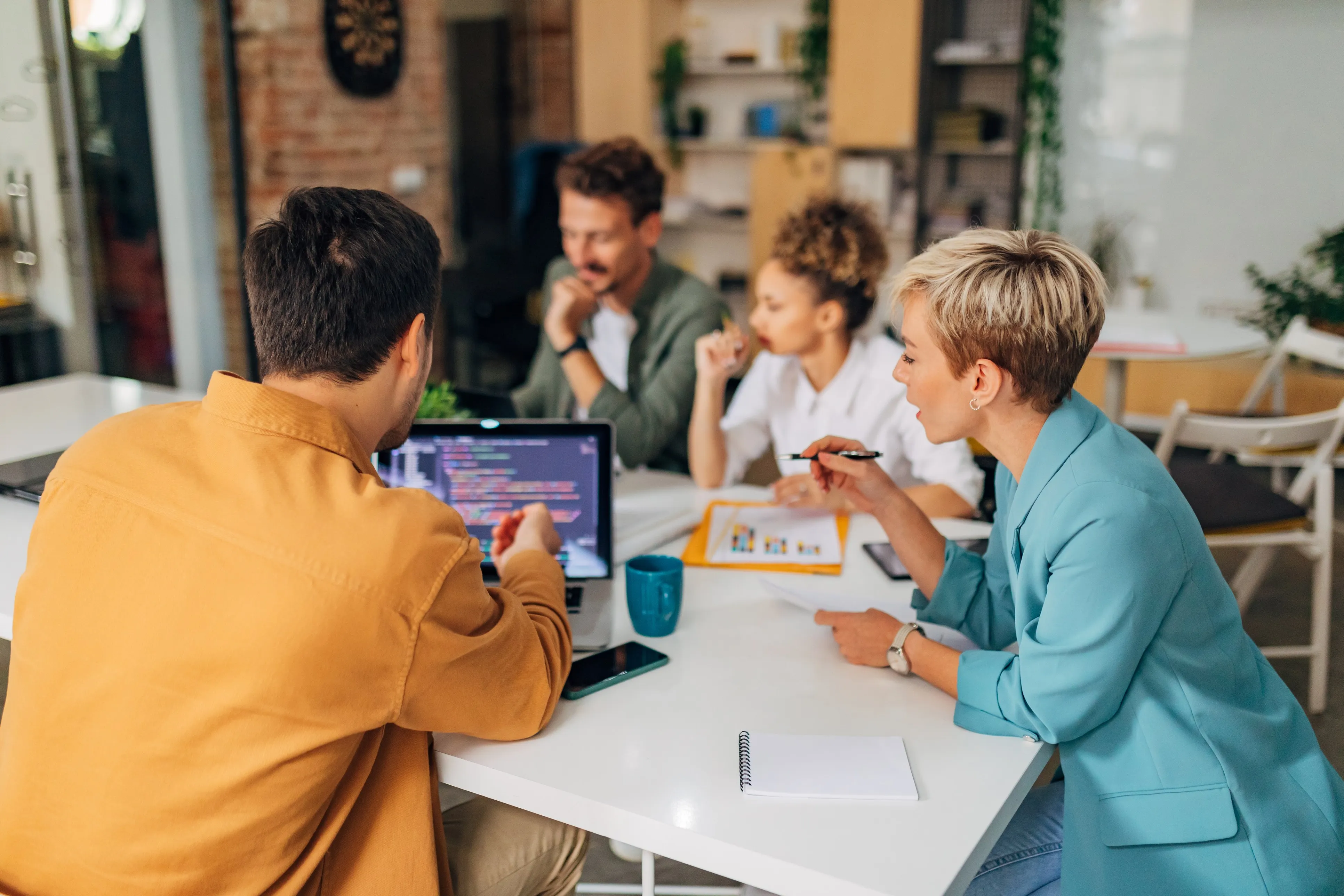 A team reviewing work on laptops around an office table