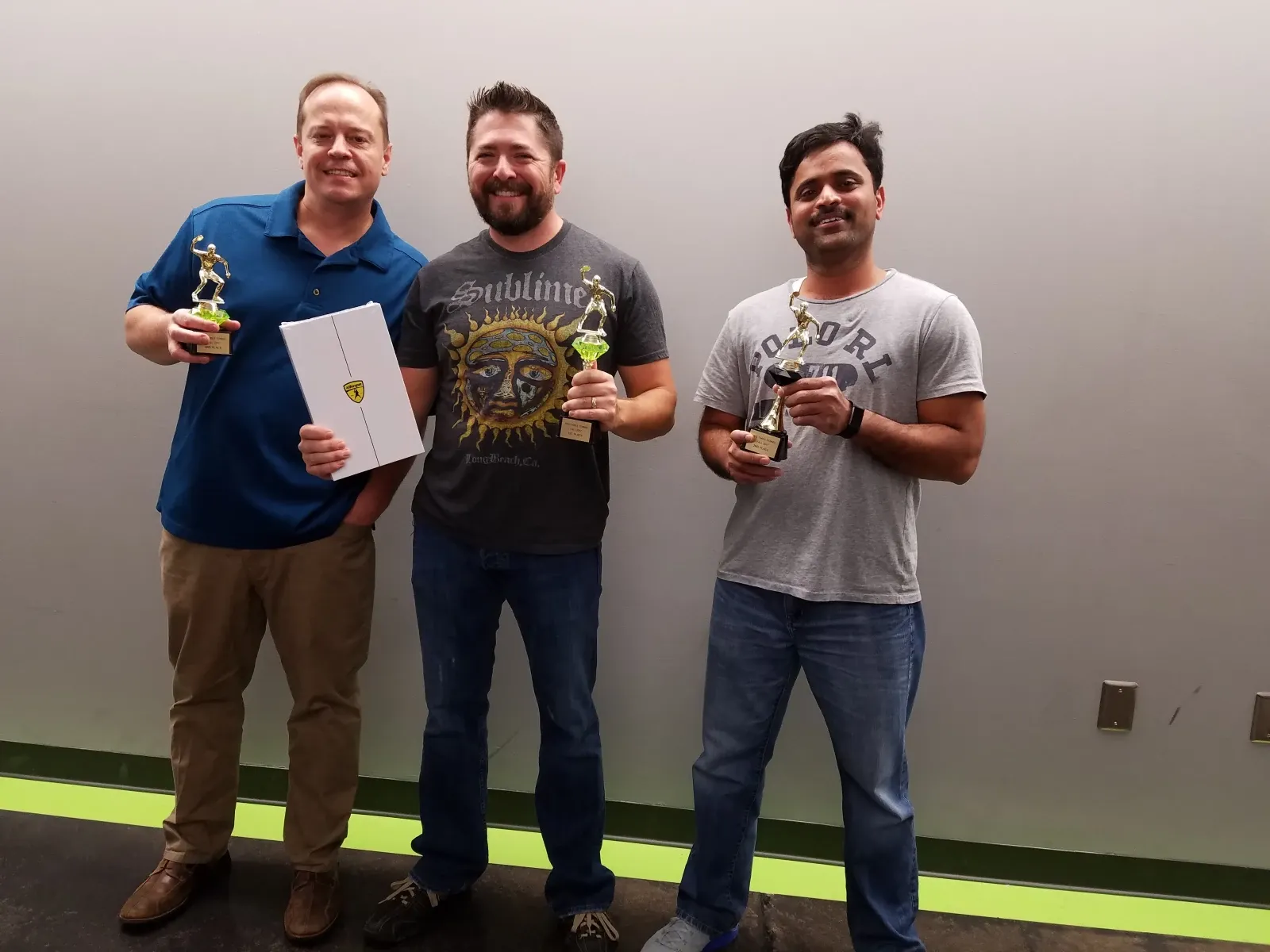 Three team members holding trophies in the office