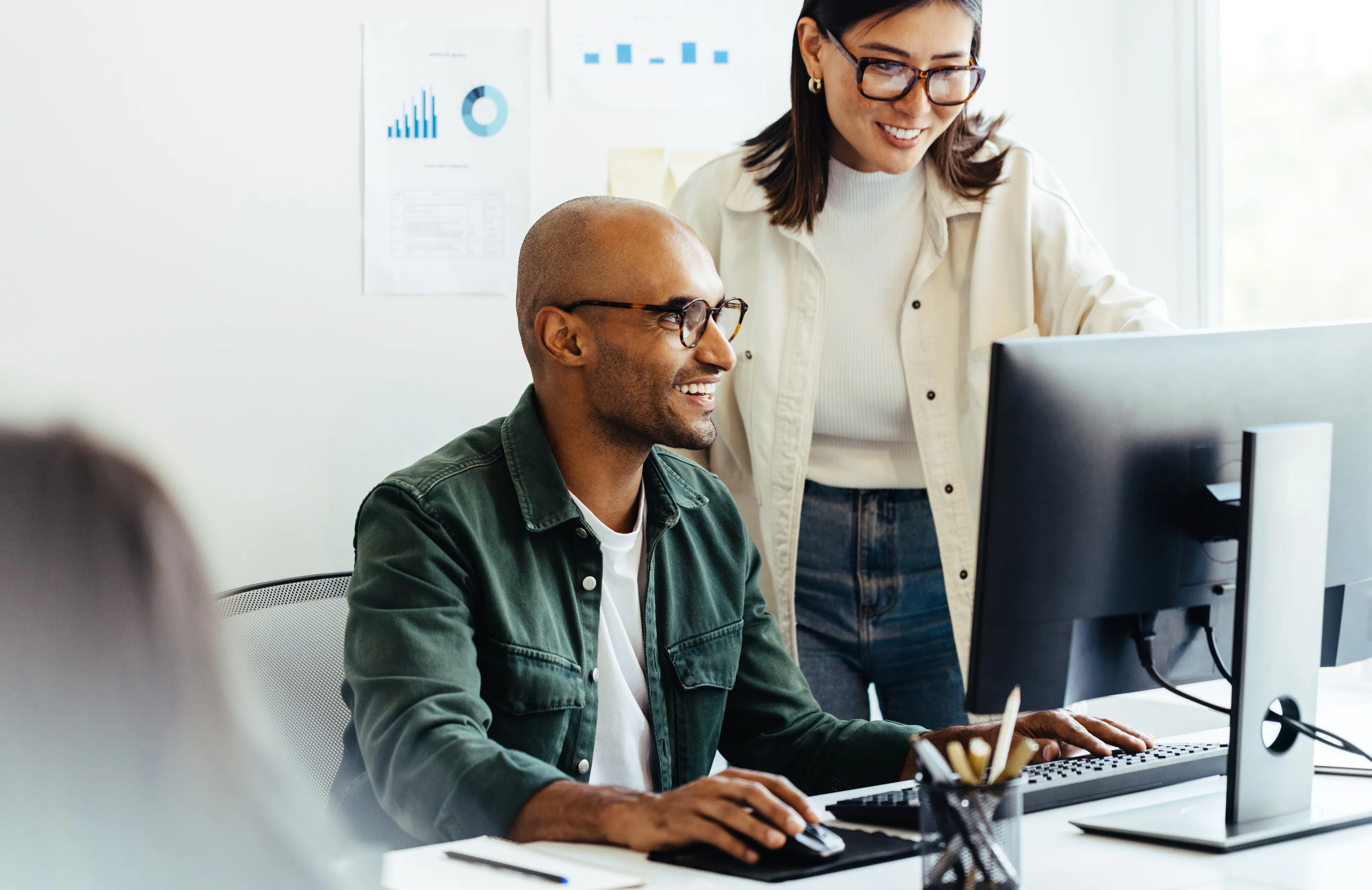 Two colleagues reviewing work at a desktop