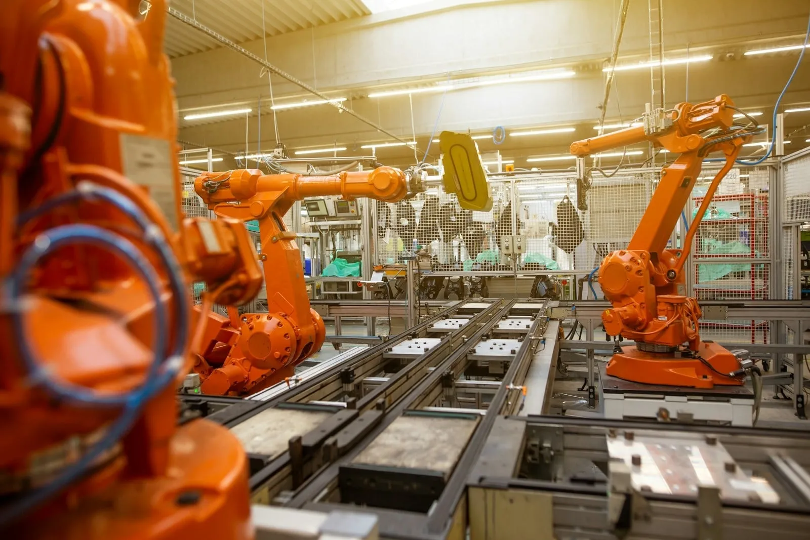 Orange industrial robot arms on a factory assembly line